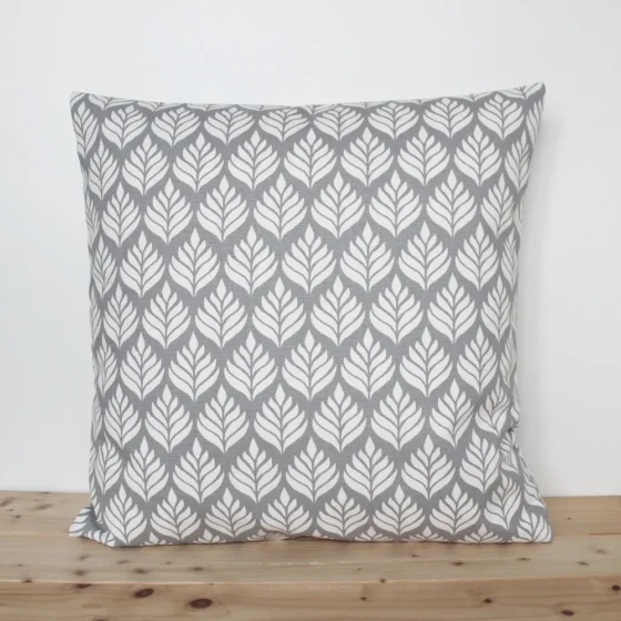 A grey and white cushion cover featuring a simple small scale floral pattern