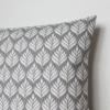 A grey and white cushion cover featuring a simple small scale floral pattern