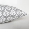 A grey and white cushion cover featuring a simple small scale floral pattern